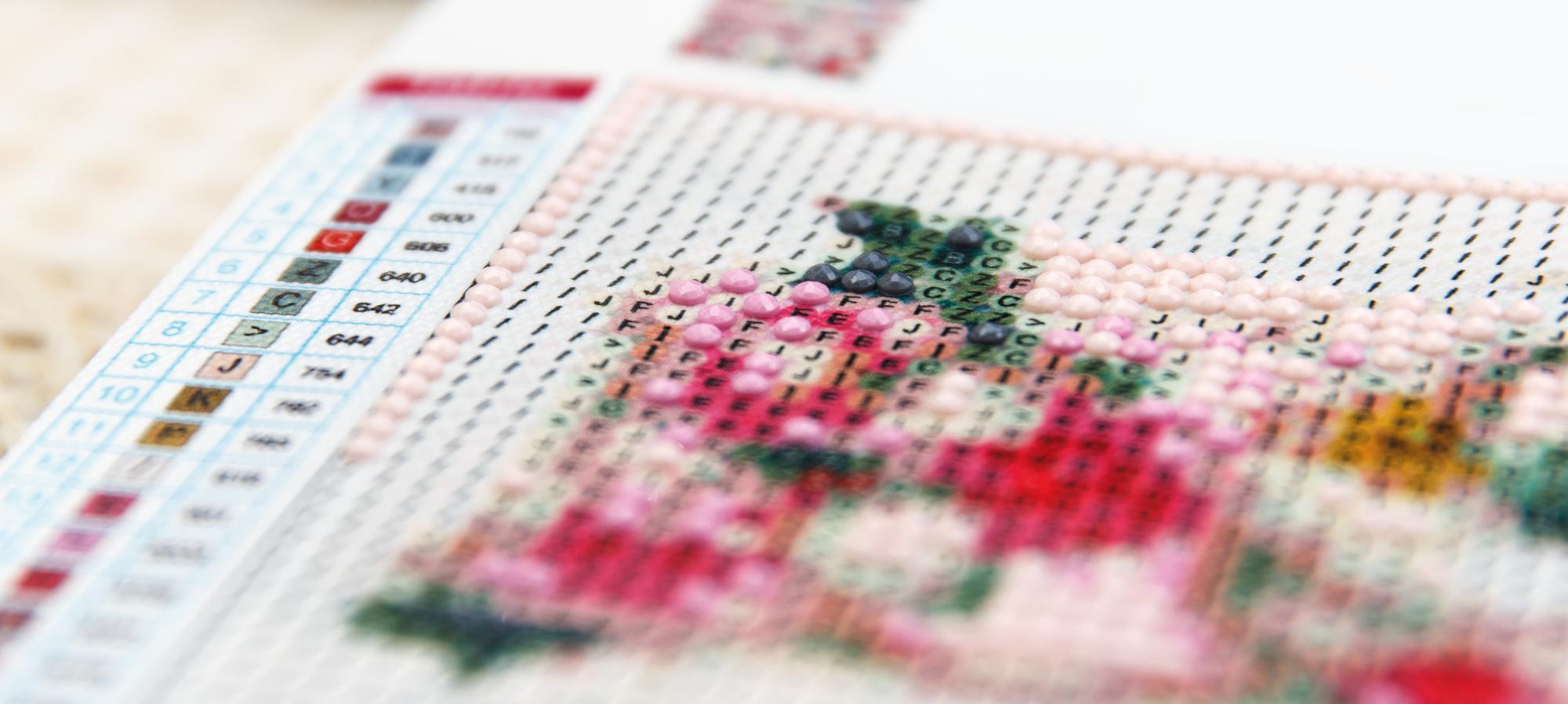 Digitally plotted embroidery pattern on screen beside hand-stitched sample